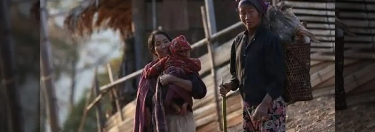A mother carrying her child beside another woman carrying firewood in a Naga village, Sagaing Region