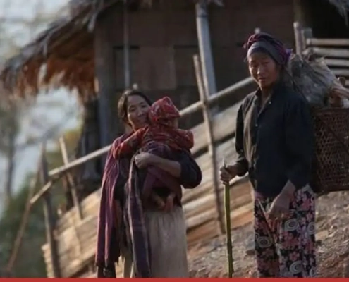 A mother carrying her child beside another woman carrying firewood in a Naga village, Sagaing Region