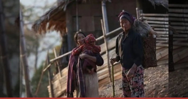 A mother carrying her child beside another woman carrying firewood in a Naga village, Sagaing Region