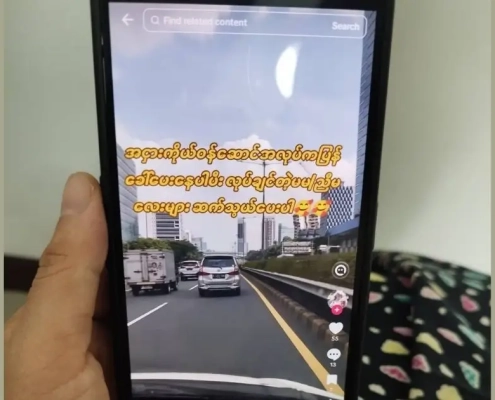 Hand holding a phone showing a TikTok video advertising factory job recruitment with high pay for young workers, illustrating the online job scams targeting unemployed garment workers