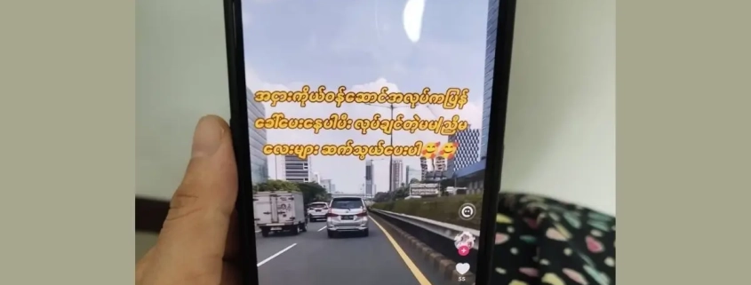 Hand holding a phone showing a TikTok video advertising factory job recruitment with high pay for young workers, illustrating the online job scams targeting unemployed garment workers